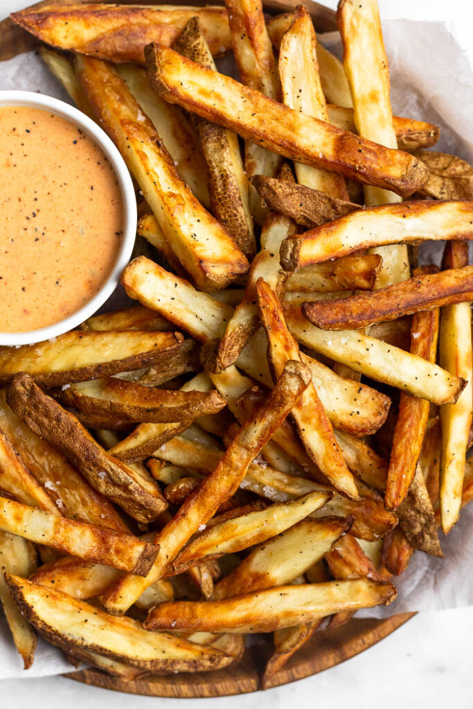 Overhead shot of a plate of air fryer french fries with a small ramekin of sauce.