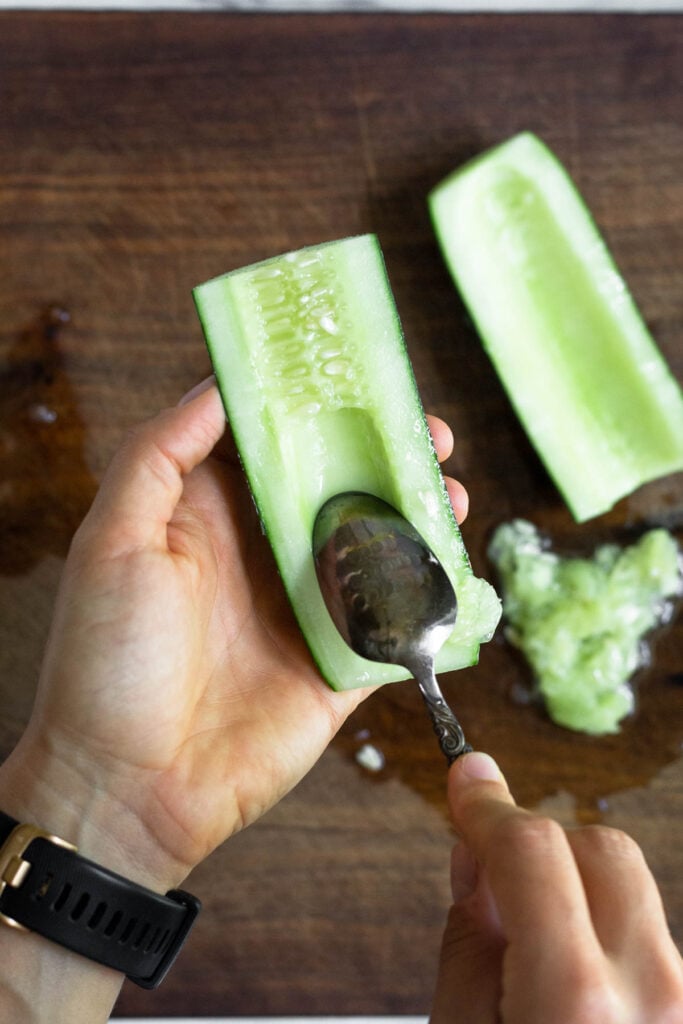 Overhead shot of half cucumber with a spoon scooping out the seeds.