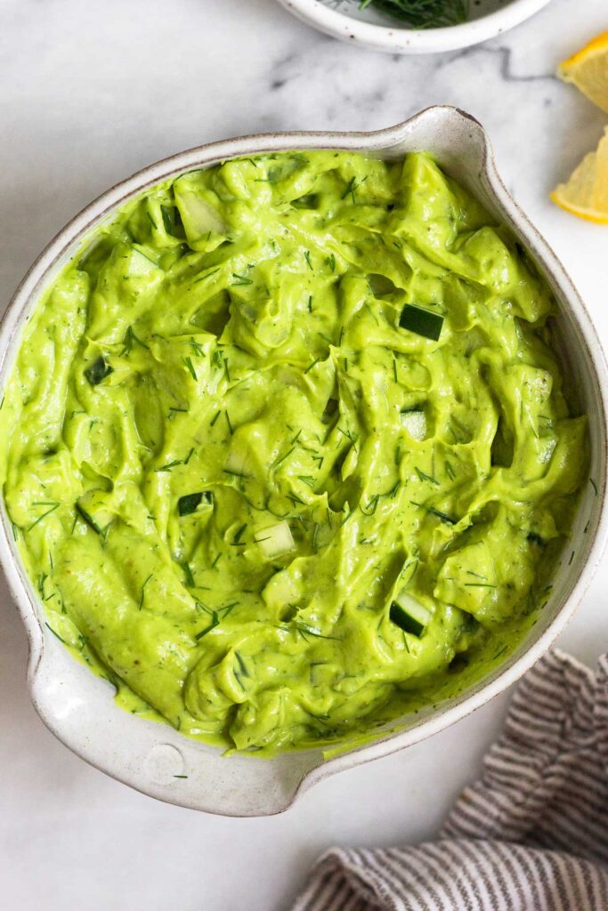 Overhead shot of avocado tzatziki in a bowl sprinkled with dill.