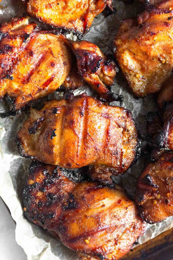 Overhead shot of grilled marinated chicken thighs on a baking sheet.