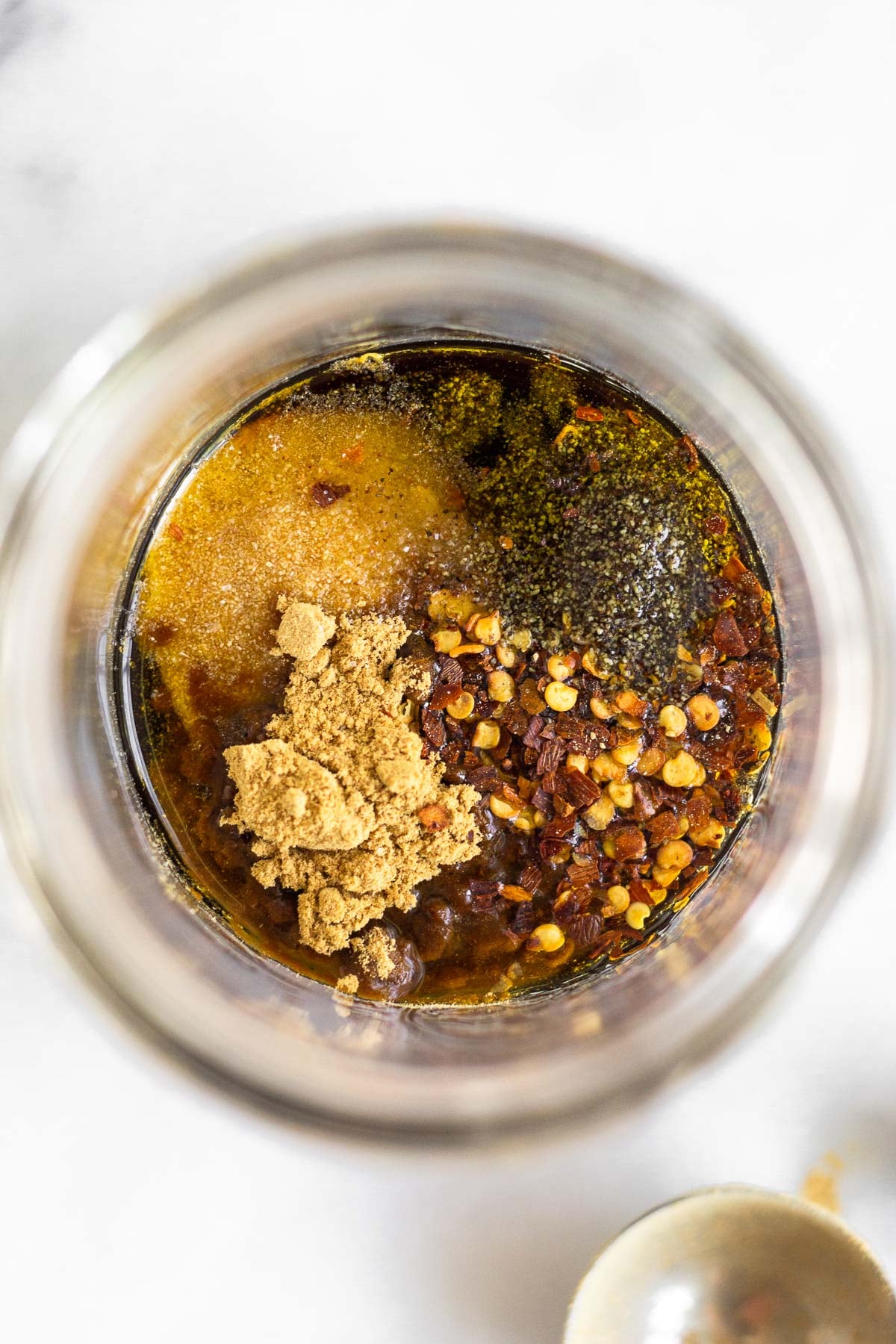 Glass jar filled with coconut amino, oil, and spices.