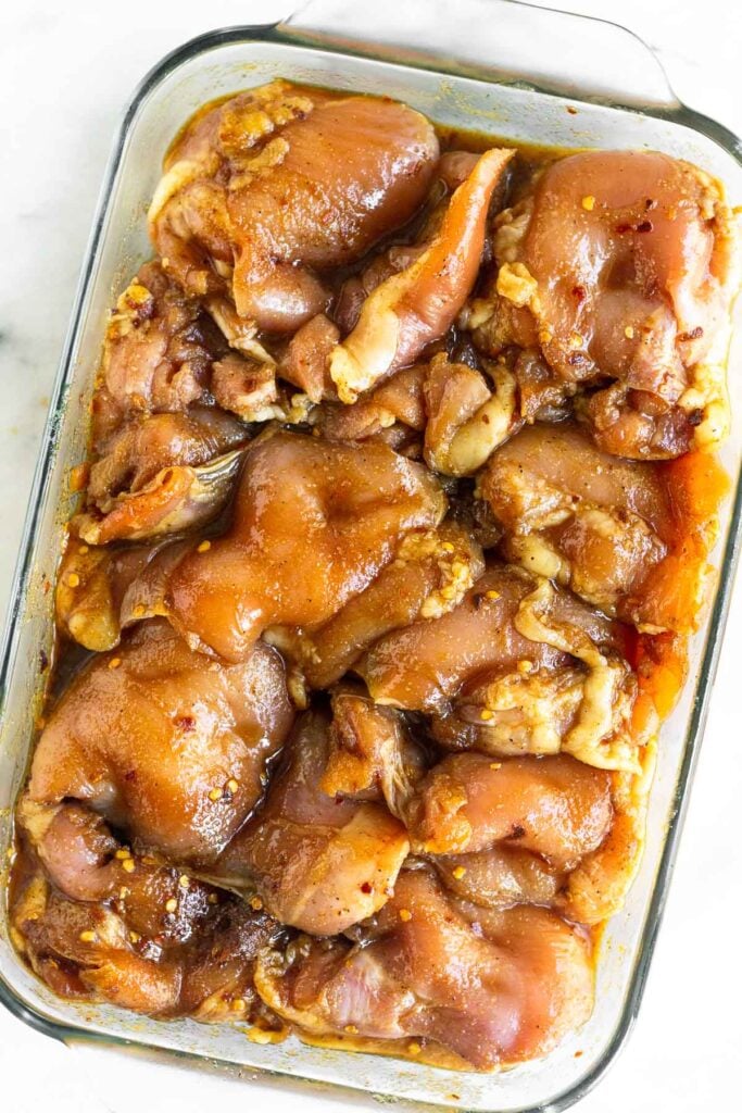 Overhead shot of chicken thighs in a baking dish marinating.