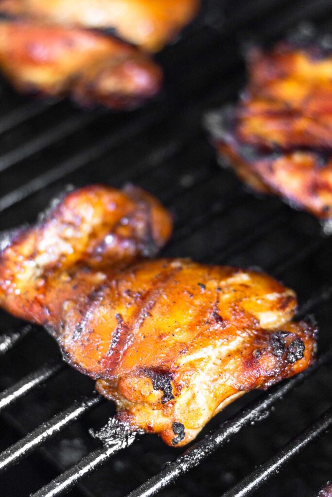 Close up of a grilled chicken thigh on the grill.