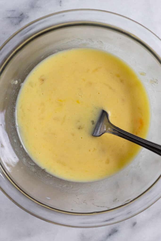 A glass bowl with a wet batter with a fork in it.
