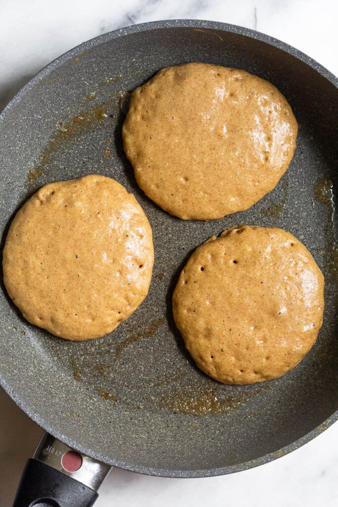 Large skillet with pancakes on it before they are flipped.