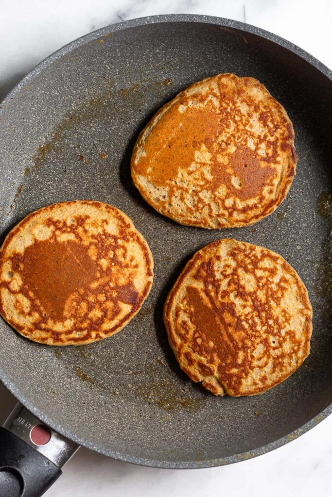 Skillet with three protein pancakes in it.