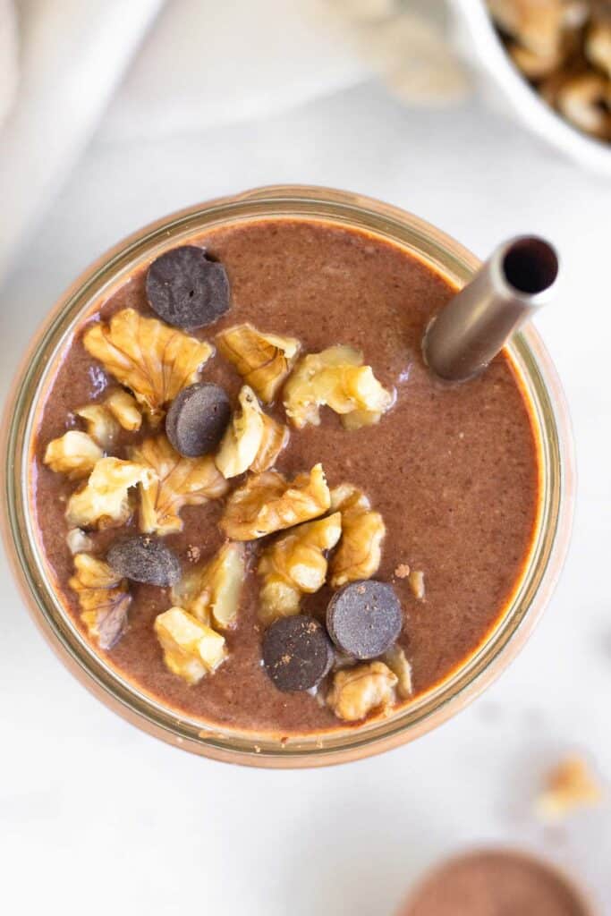 Overhead shot of a chunky monkey smoothie topped with walnuts and chocolate chips.