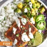 Fish taco bowl with cilantro white rice, pineapple salsa, cabbage, seasoned fish, and white sauce in a bowl. Around it is a plate of jalapeños, a bowl of salsa, and another fish taco bowl.
