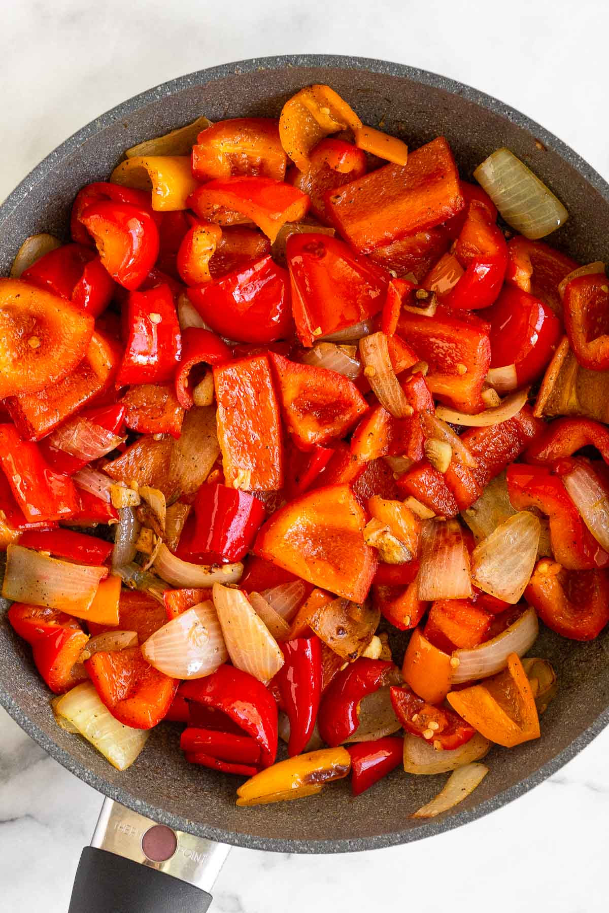 Saute pan filled with sautéed pepper, onions, and garlic.