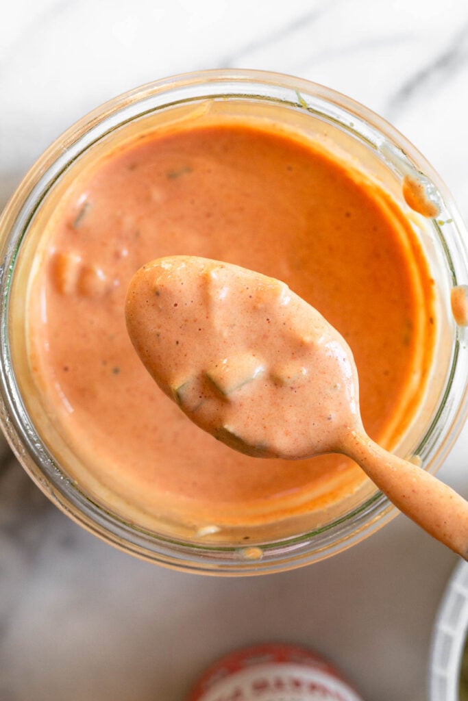 Overhead shot of special sauce for burgers in a jar with a spoon holding some above the jar.