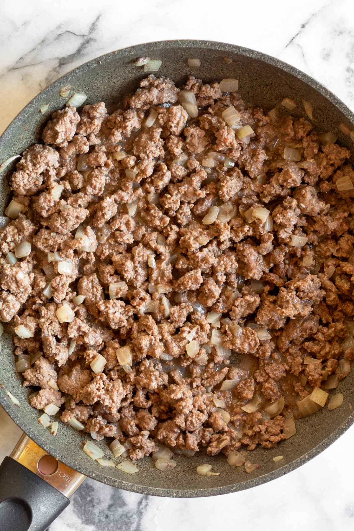 Mustard fried ground beef in a skillet.