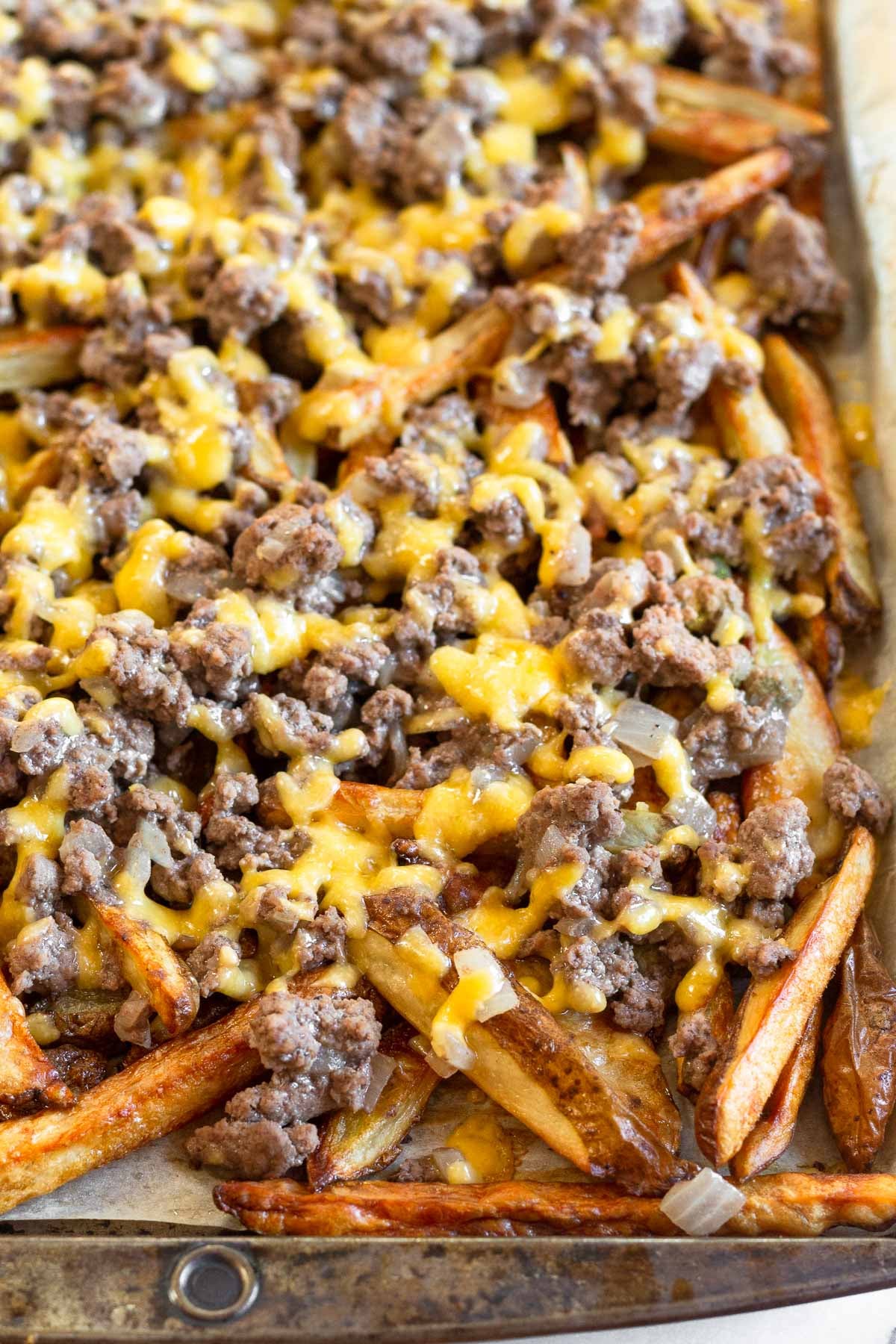 A baking sheet full of french fries topped with ground beef and melted cheese.