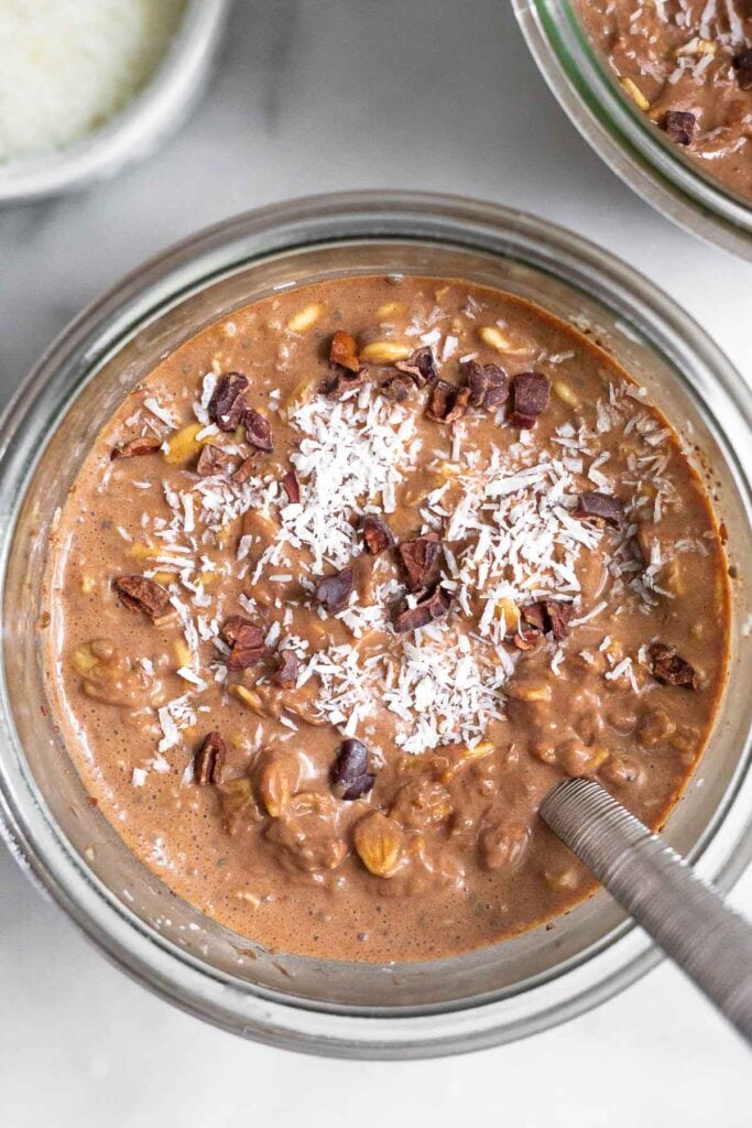Overhead shot of chocolate coconut overnight oats topped with shredded coconut and cacao powder.