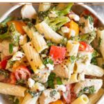Goat cheese pasta in a bowl topped with fresh herbs.