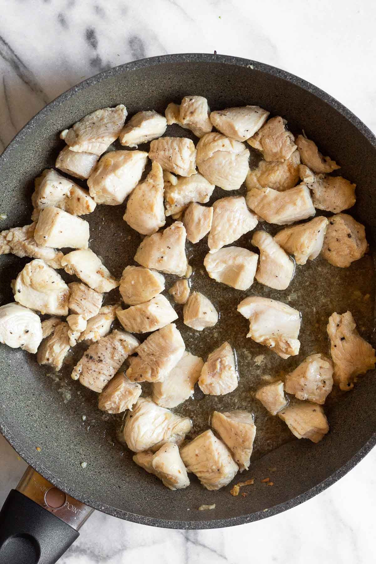 Saute pan filled with sautéed diced chicken.