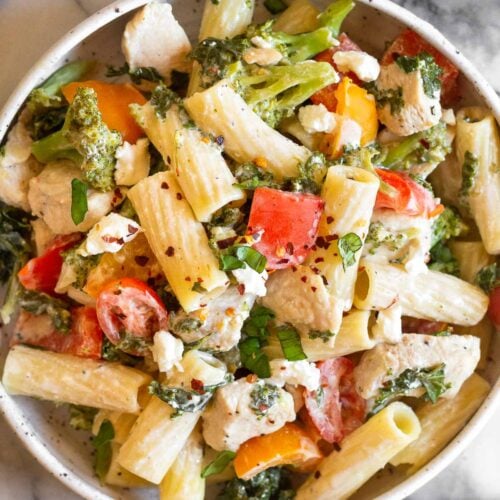 Goat cheese pasta in a bowl topped with fresh herbs.