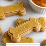 Healthy pumpkin peanut butter dog treats on a white counter with some stacked on top of each other.