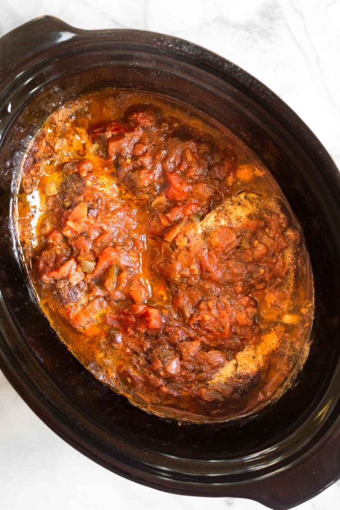 Cooked pork chops with salsa in a slow cooker.