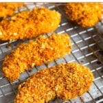 Buffalo chicken tenders on a wire cooling rack on a baking sheet.