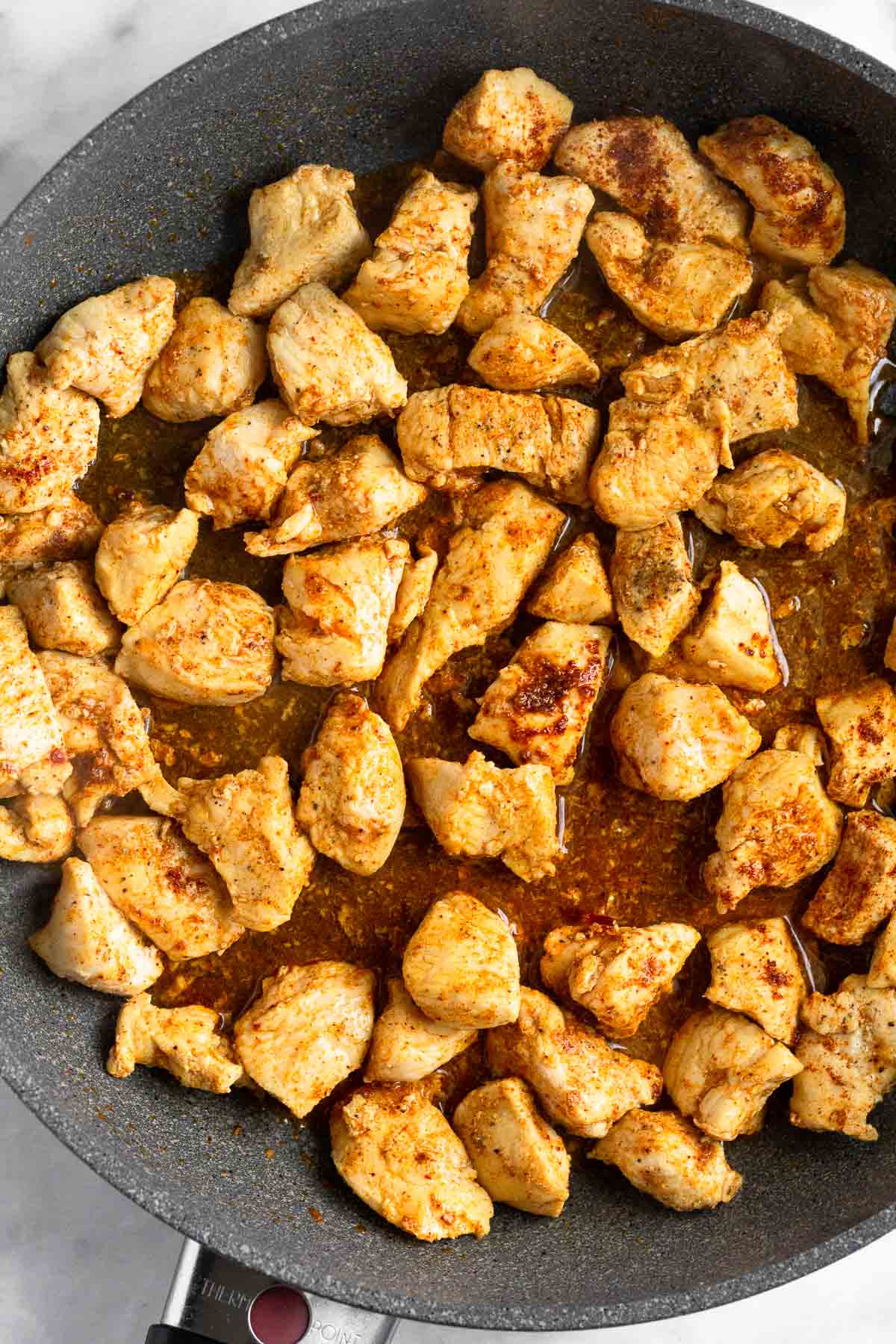 Pan filled with sautéed pieces of chicken and spices.