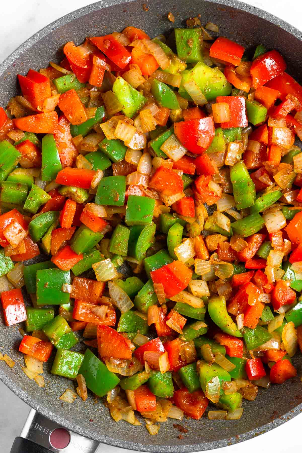 Pan filled with sautéed peppers and onions.