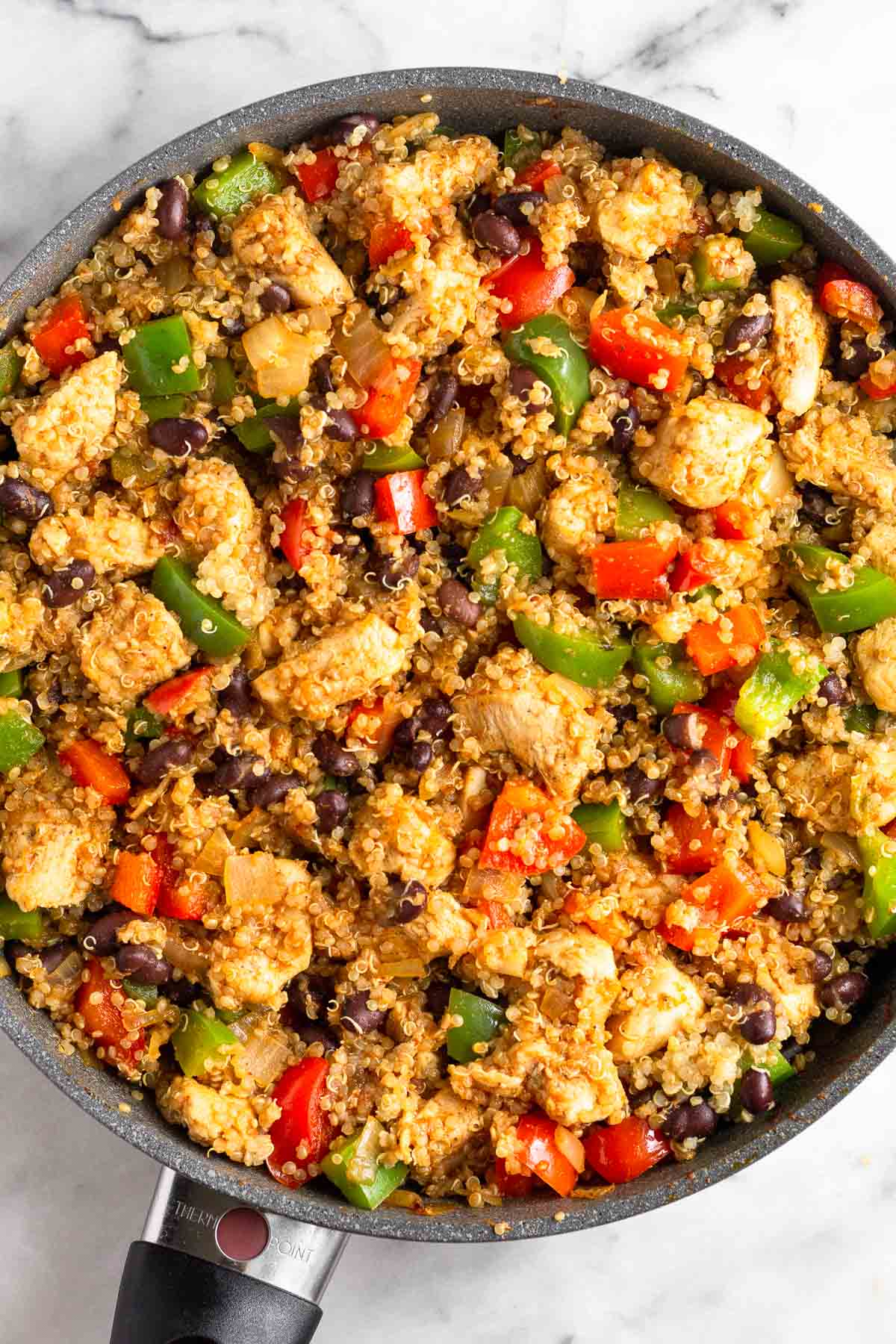 Large pan filled with a mixture of chicken, quinoa, veggies, and black beans.
