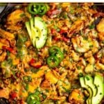 Healthy casserole recipe with chicken, rice, veggies, and cheese in a large cast iron. It is topped with avocado, jalapeños, and cilantro.
