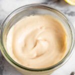 Homemade mayo in a jar with half a lemon and an egg next to it.