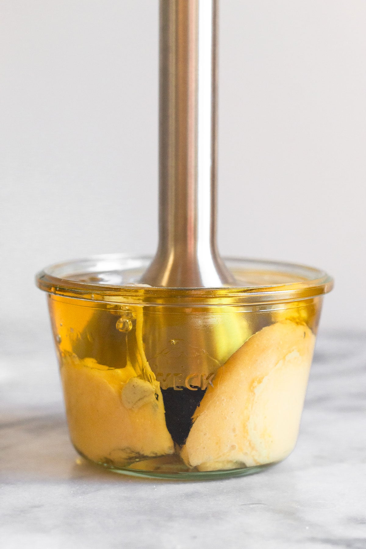 Jar with an immersion blender in it starting an emulsion for homemade mayo.