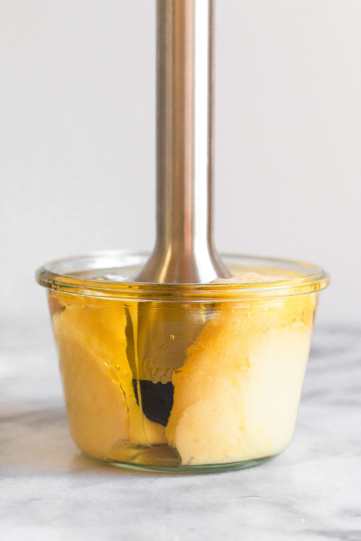 An immersion blender in a jar making homemade mayonnaise.
