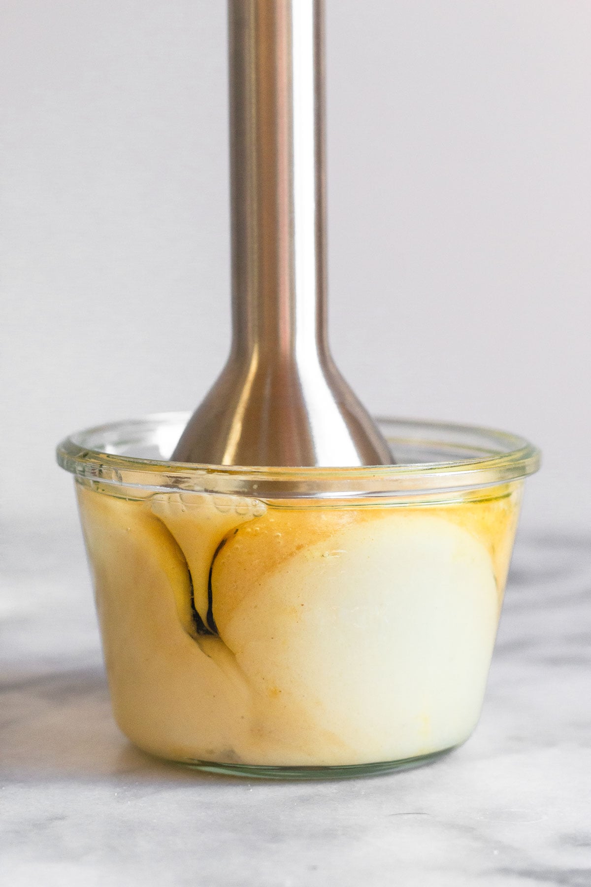 An immersion blender in a jar making homemade mayonnaise.