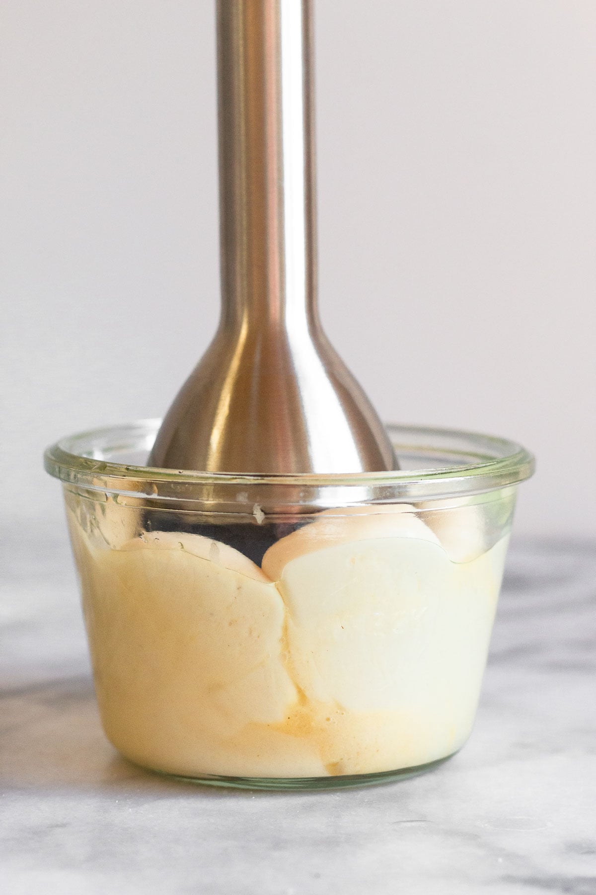 Homemade mayo in a jar being made with am immersion blender.