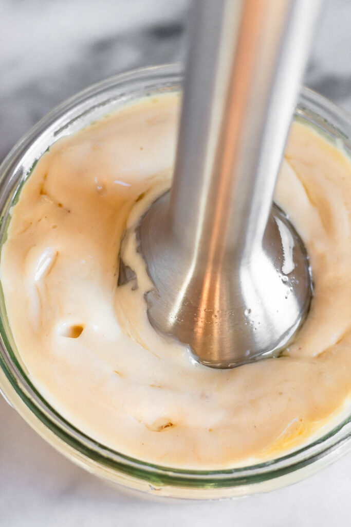 Overhead shot of homemade mayo being made with an immersion blender in it.