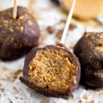 Close up of a protein cake pop with a bite taken out of it. Around it is more cake pops and a spoonful of peanut butter.