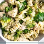 Bowl of chicken and broccoli pasta with ranch dressing. Next to is is another bowl, half a lemon, and some parsley.