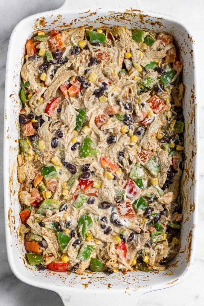 Baking dish with a baked mixture of shredded chicken, veggies, black beans, corn, spices, salsa, and greek yogurt.