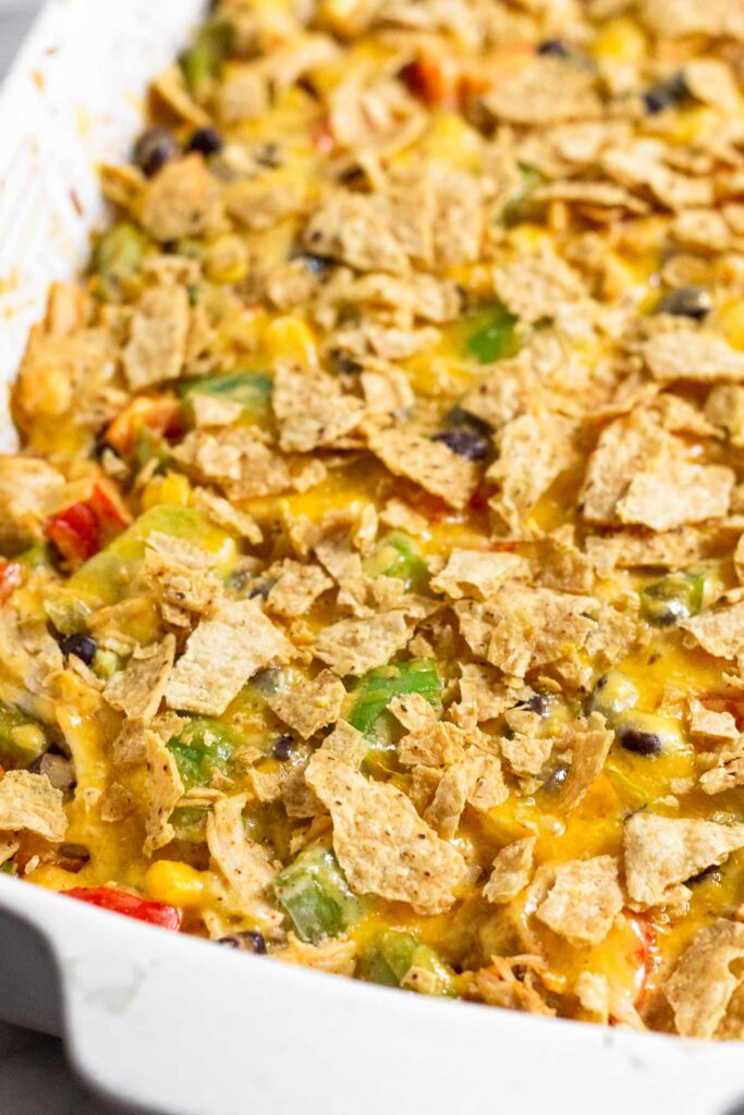 Chicken taco casserole with tortilla chips and melted cheese in a large baking dish.