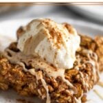 Close up a gingerbread oatmeal bar on a plate. It is topped with yogurt and nut butter and sprinkled with cinnamon.