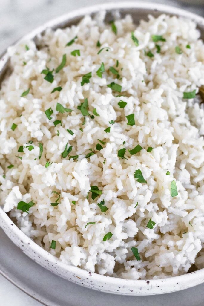 Close up of a bowl of coconut rice sprinkled with fresh cilantro.