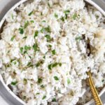 Overhead shot of Instant Pot coconut rice in a bowl topped with fresh cilantro. A spoon is also in the bowl.