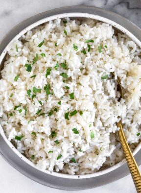 Overhead shot of Instant Pot coconut rice in a bowl topped with fresh cilantro. A spoon is also in the bowl.
