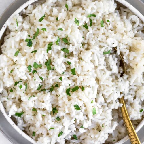 Overhead shot of Instant Pot coconut rice in a bowl topped with fresh cilantro. A spoon is also in the bowl.