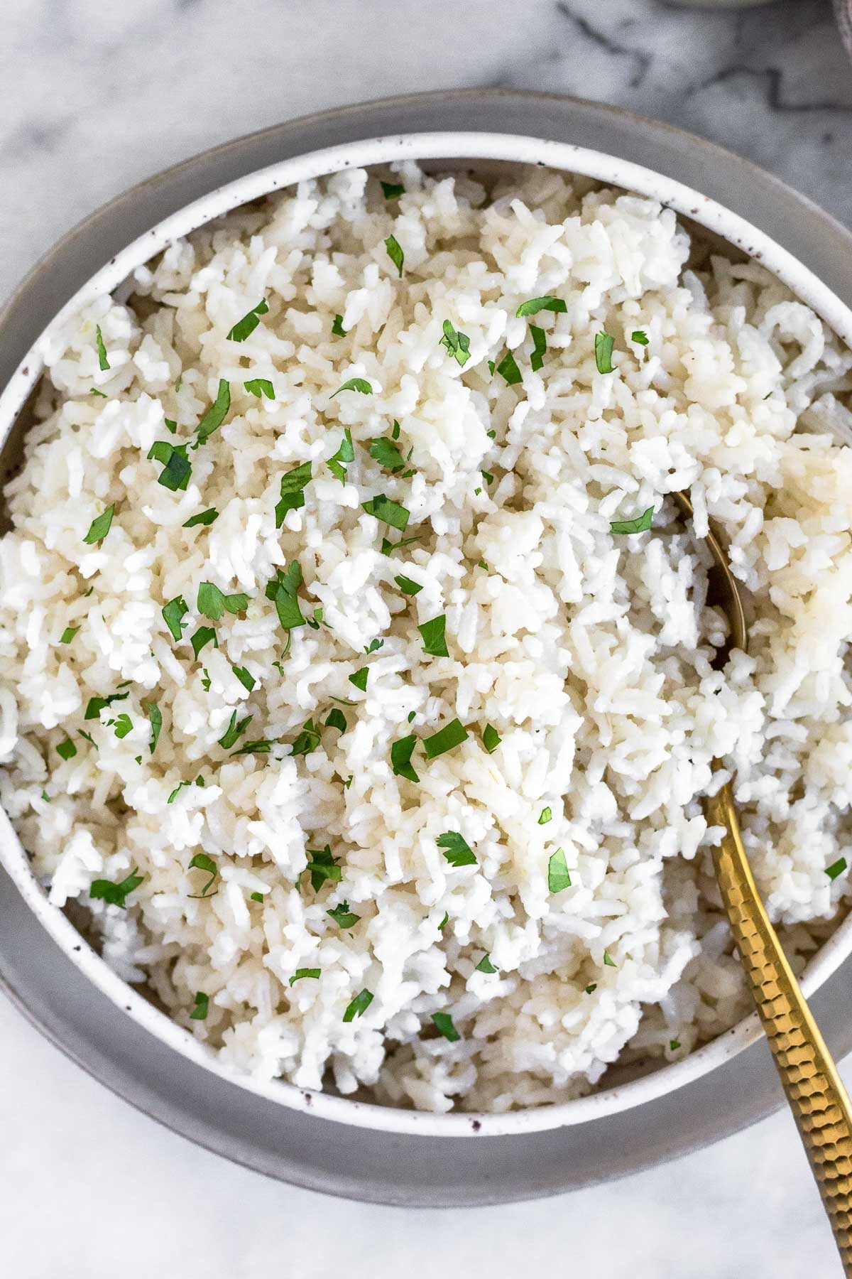 Overhead shot of Instant Pot coconut rice in a bowl topped with fresh cilantro. A spoon is also in the bowl.