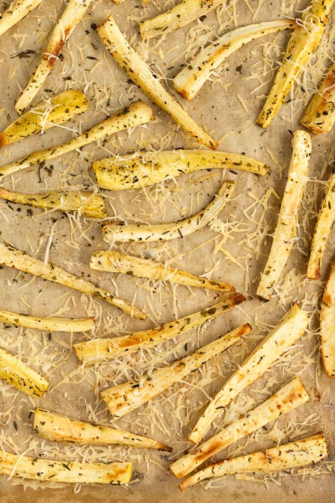 A baking sheet filed with parsnips that have been roasted with herbs and parmesan cheese.