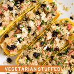 Vegetarian squash stuffed with quinoa, apples, cranberries, goat cheese, and pumpkin seeds lined up next to each other on a baking sheet.