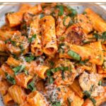 Chicken sausage pasta on a plate topped with basil and parmesan cheese.
