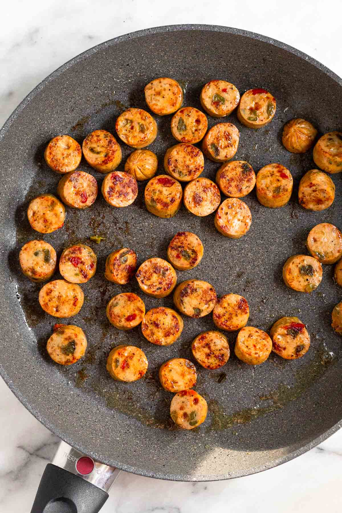 Saute pan filled with sautéed rounds of chicken sausage.