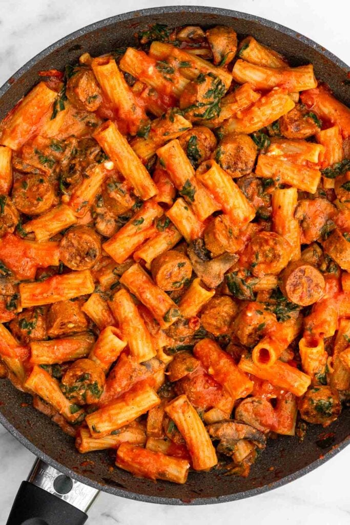 Large skillet filled with pasta, chicken sausage, and veggies all tossed with marinara sauce.