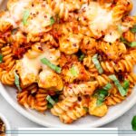Chicken parmesan pasta in a bowl topped with fresh basil.