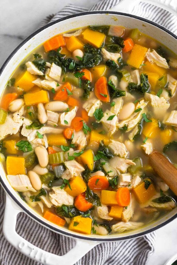 Large pot of soup with turkey, butternut squash, veggies, kale, and white beans.